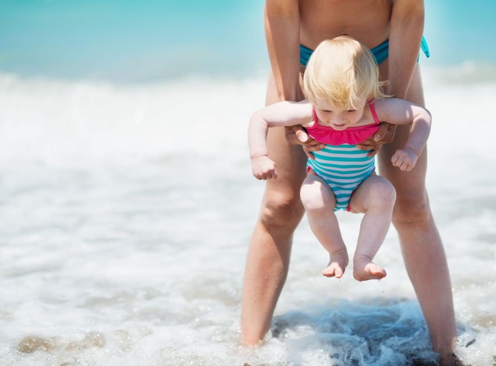 dad holding toddler above ocean - best hilton resorts for families