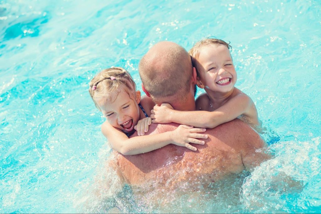kids hugging dad in pool - best hilton resorts for families
