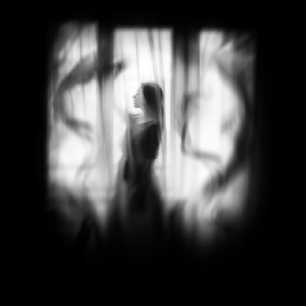 Eerie image of woman behind a curtain - most haunted hotels in the united states