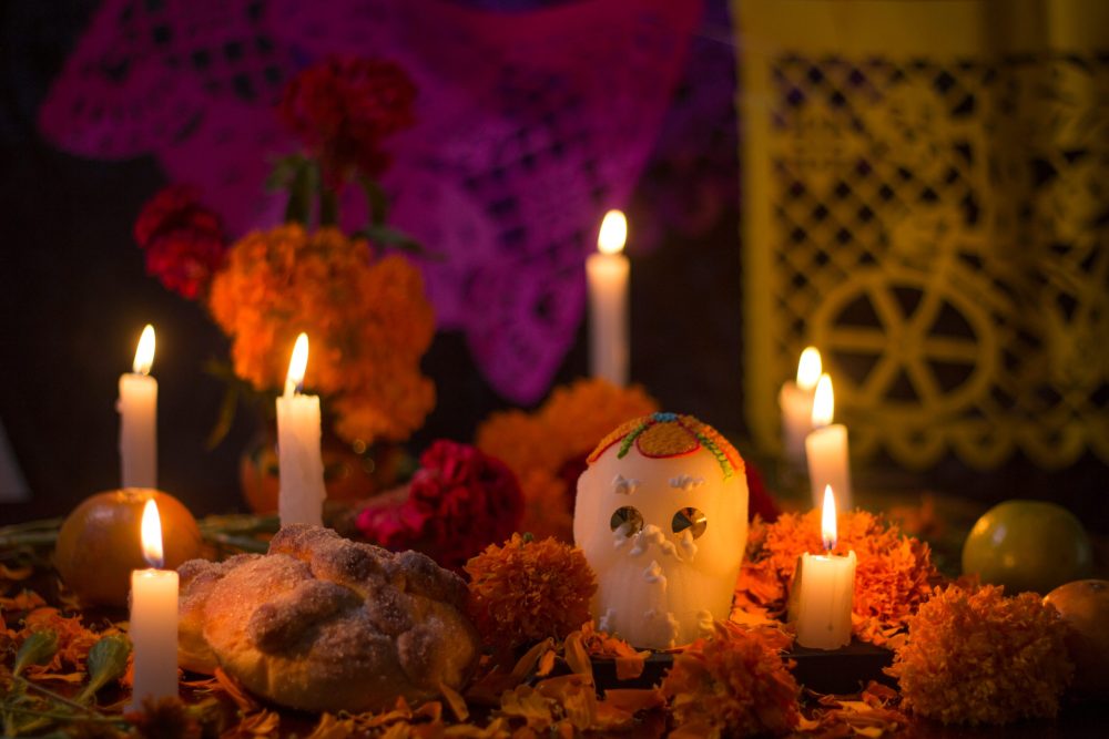 Day of the Dead altar with glowing candles, a sugar skull, and marigolds
