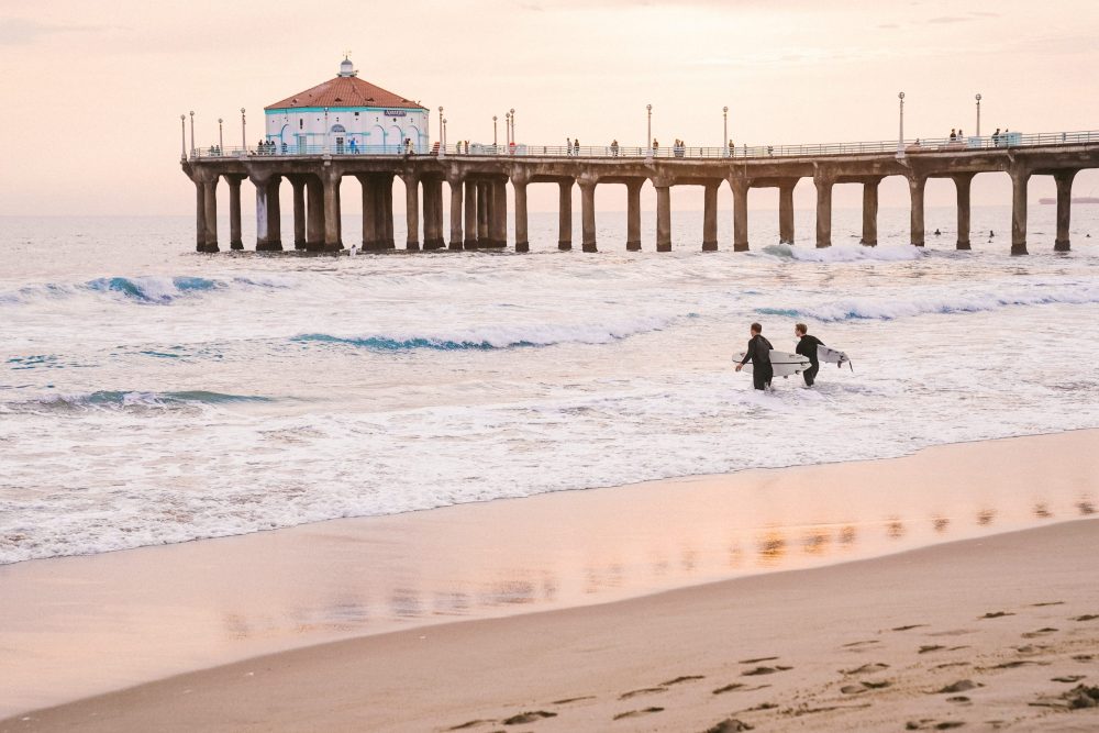 Surfing near the Manhattan Beach pier - best family beach vacations in October