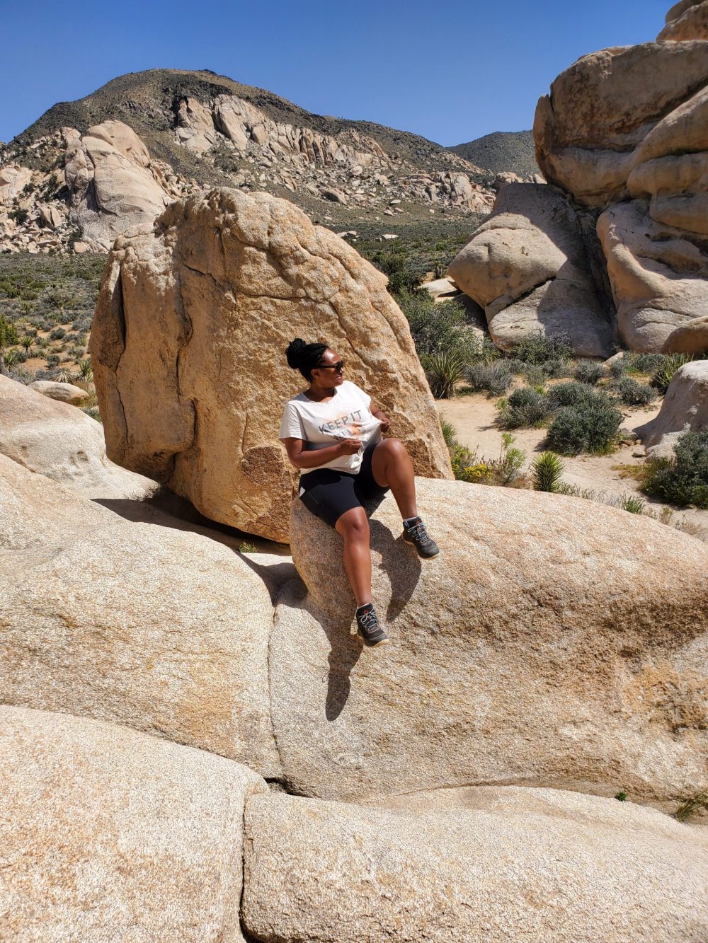 Photo of woman sitting on top of boulders at Joshua Tree National Park