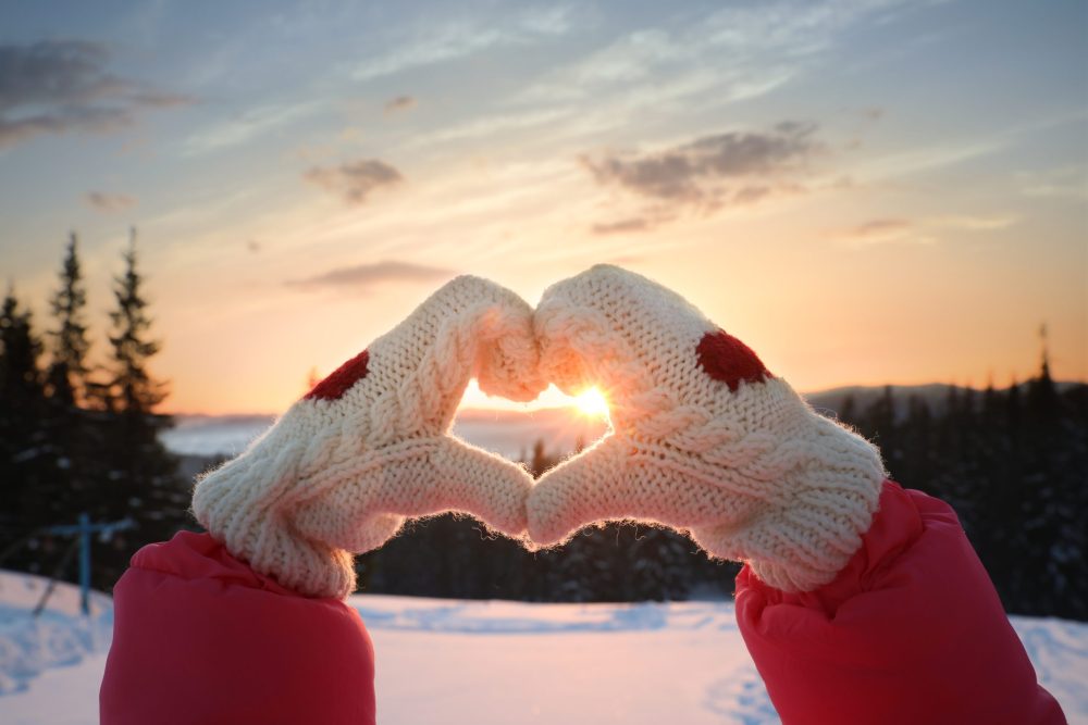 mittened hand heart on snowy mountain