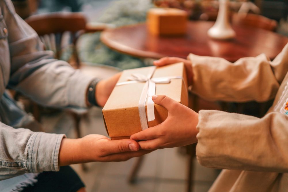 close up of hands exchanging a brown paper wrapped gift