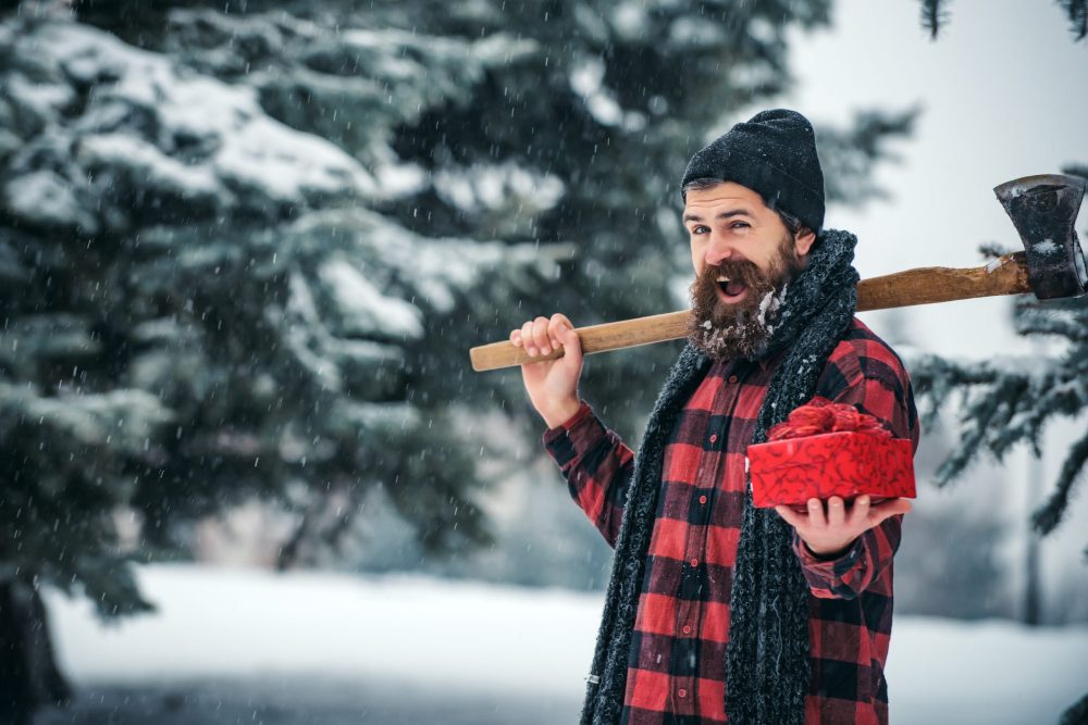 lumberjack hipster man in red and black checked shirt holding a gift and an axe