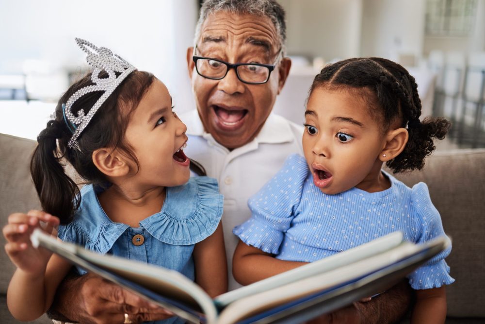 Grandpa reading to his twin granddaughters surprised and laughing