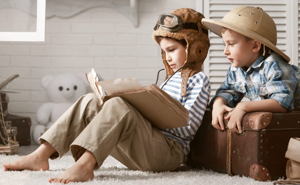 two young explorers dressed in adventure gear read a book
