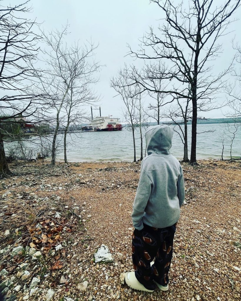 boy looking at lake and paddle boat - branson family vacations