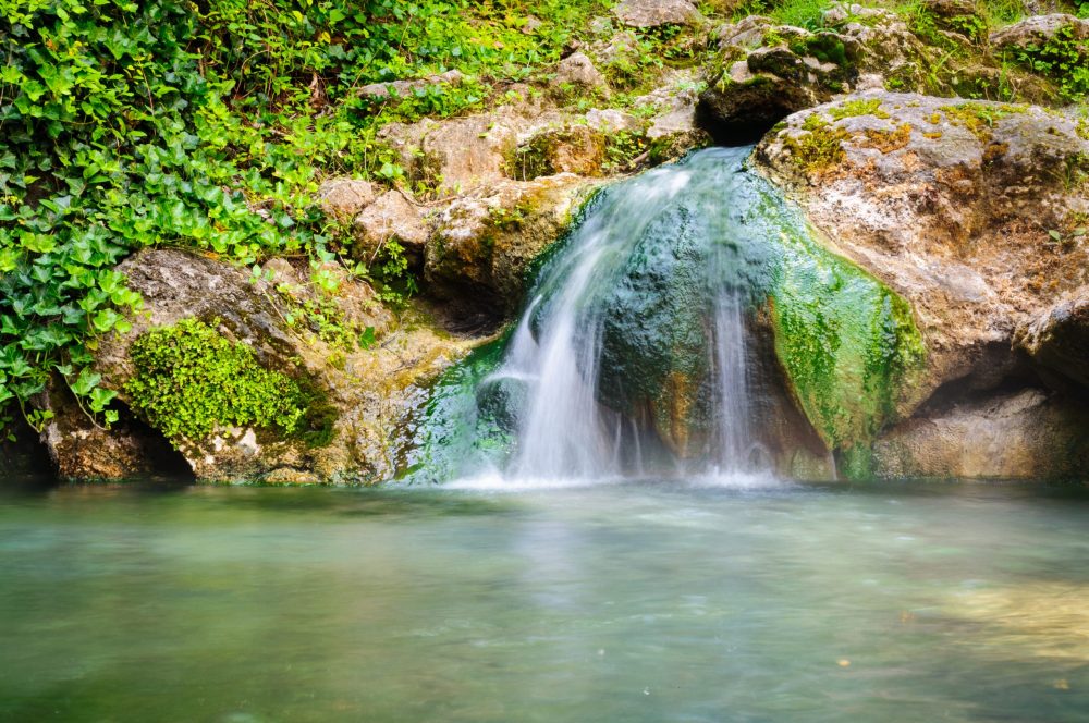 a tiny waterfall dispenses into a geothermal pool - Arkansas Hot Springs