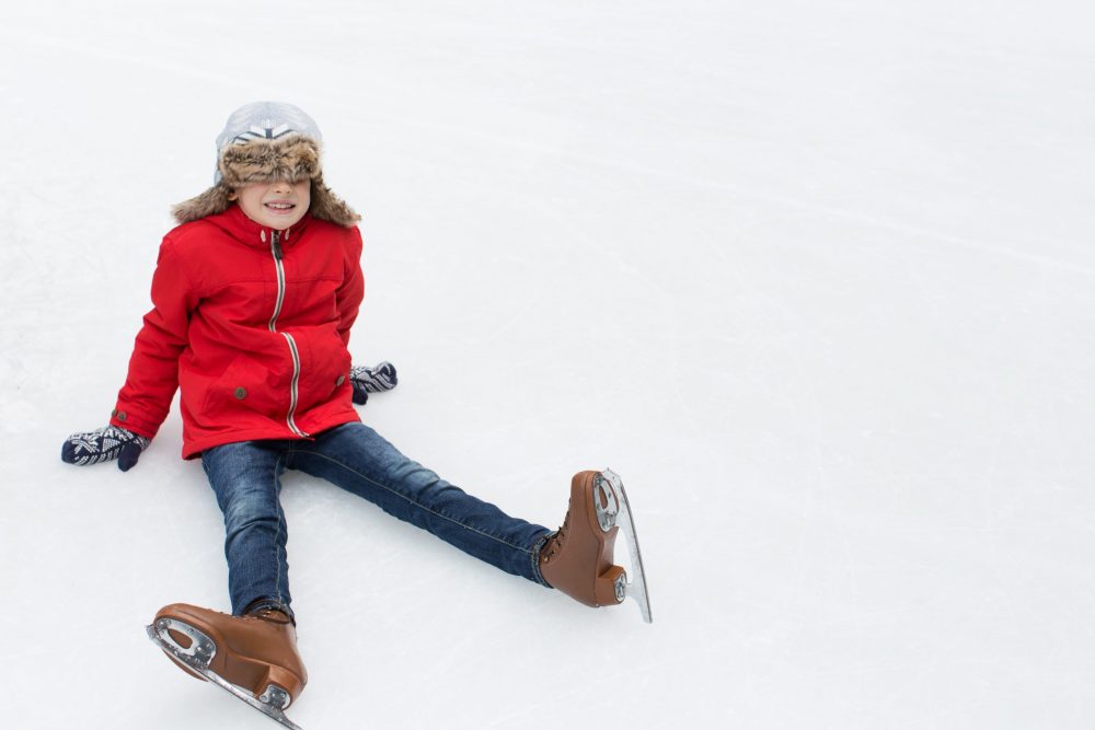 little boy in red coat fell during ice skating