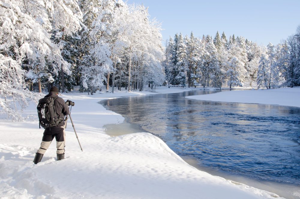 bundled up photographer prepares camera settings in a frosty tundra