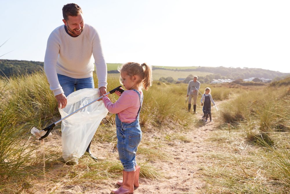 Father and daughter pick up trash from the beach. -5 Meaningful Volunteer Vacations for Families