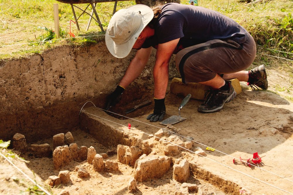 Young person measuring and digging at archeology site. -5 Meaningful Family Volunteer Vacations