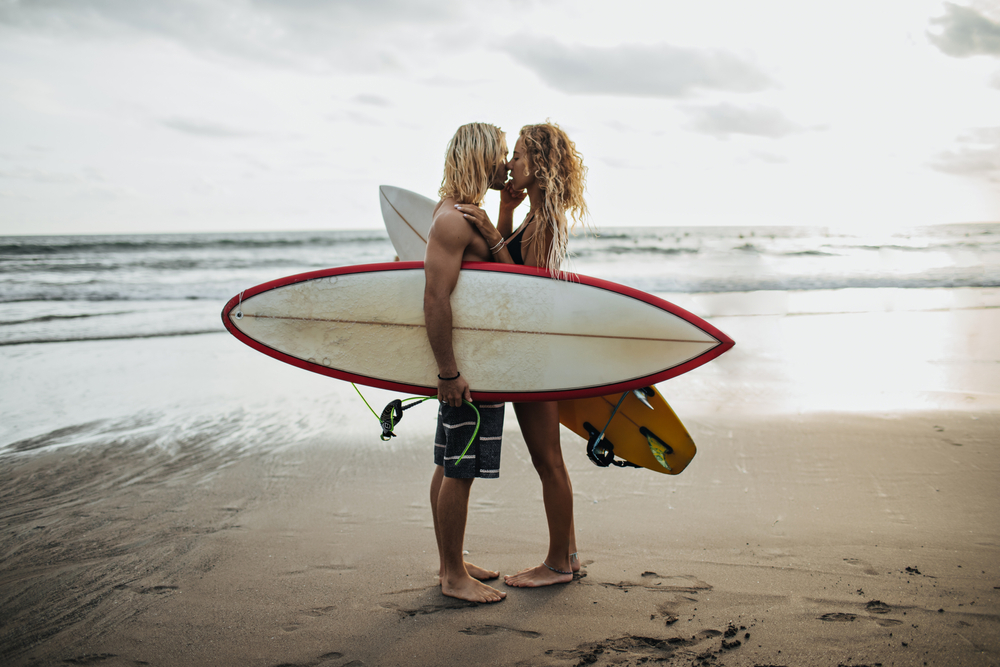 Surfer couple kissing by ocean. -best romantic escapes near LA