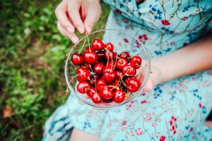 woman holding bowl of cherries