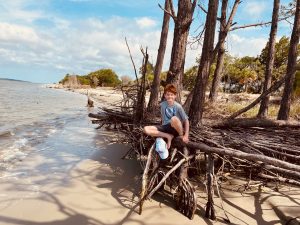 Redheaded boy sitting on tree at the foot of the Atlantic Ocean.