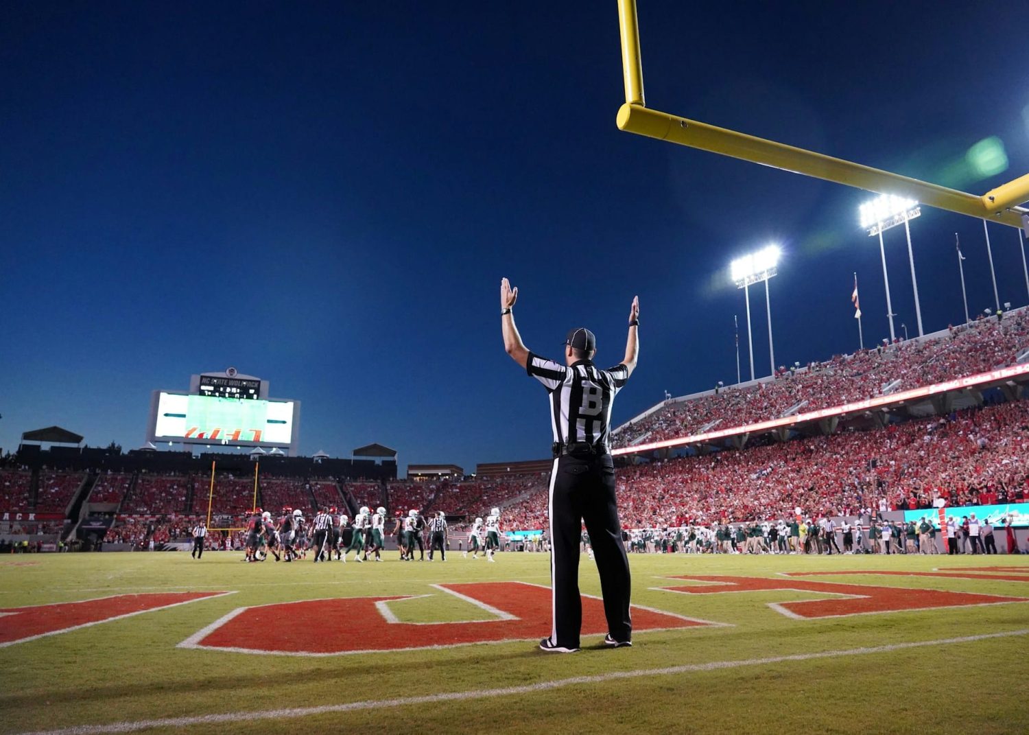 Ref standing on football field signaling a scored field goal. Best Father's Day trips.