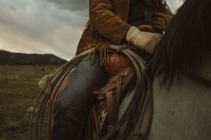 Woman riding horse with saddle and rope. Family ranch vacations Texas.