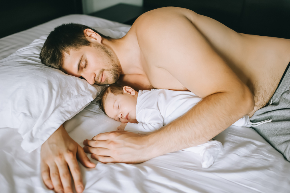 Dad and baby sleeping in bed. 