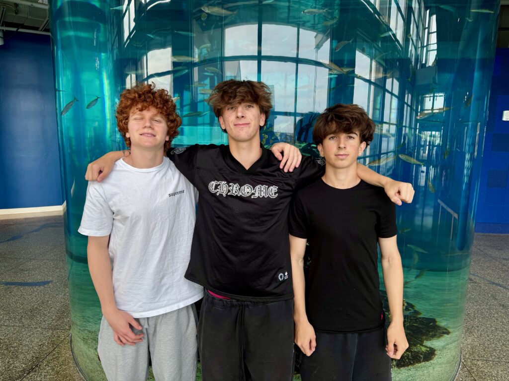 three boys in front of aquarium tank