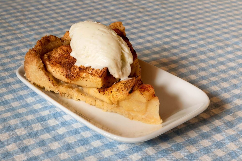 Slice of apple pie with vanilla ice cream on top.