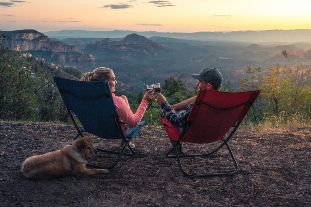 couple in camp chairs toasting from a vista - best family campsites, family travel