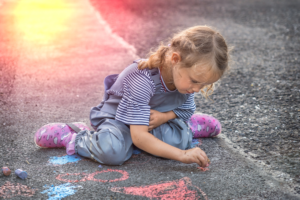 little girl drawing with chalk as sun sets Ann Arbor Art Fair