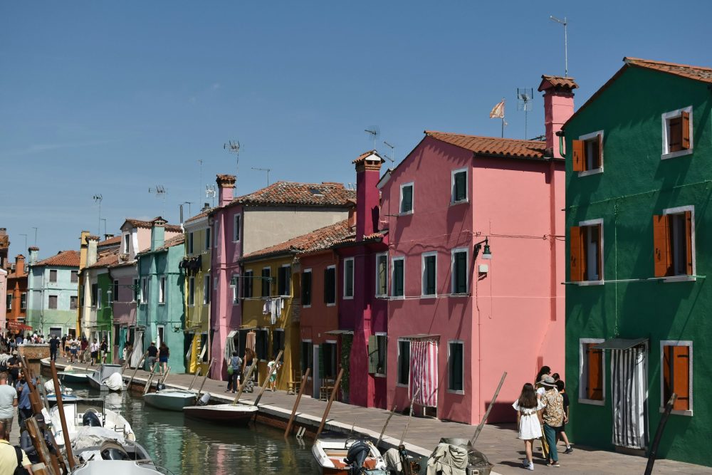 family walking on sidewalk between canal and houses