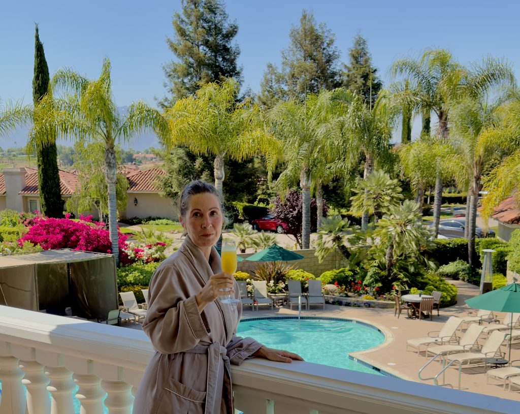 woman in robe at a spa in front of a lovely pool and vineyard