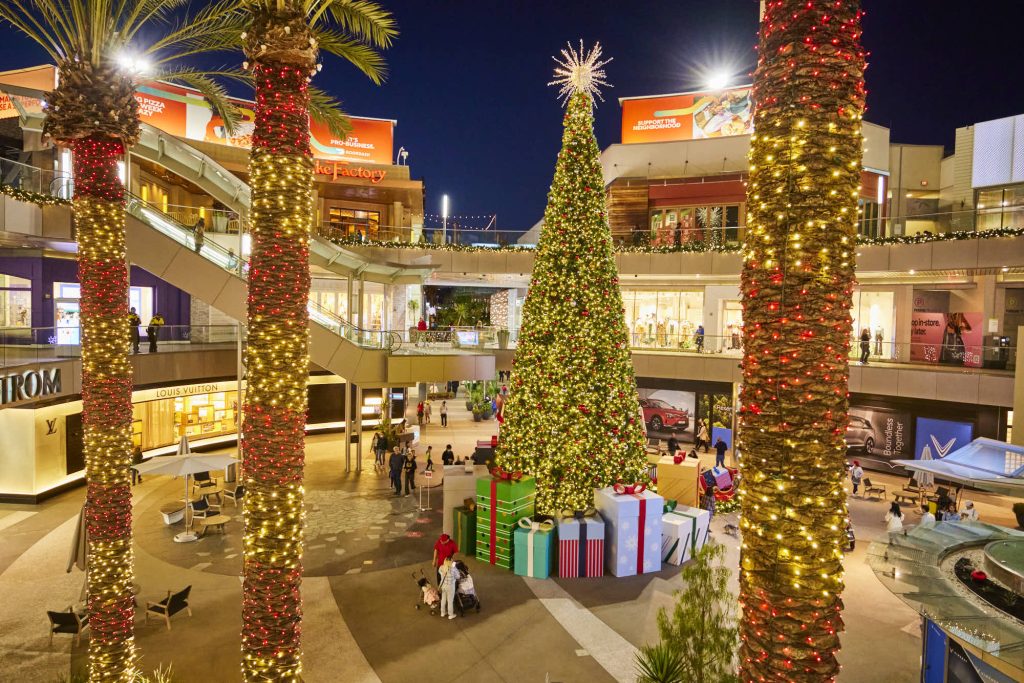 tree in middle of open air mall with gifts around.