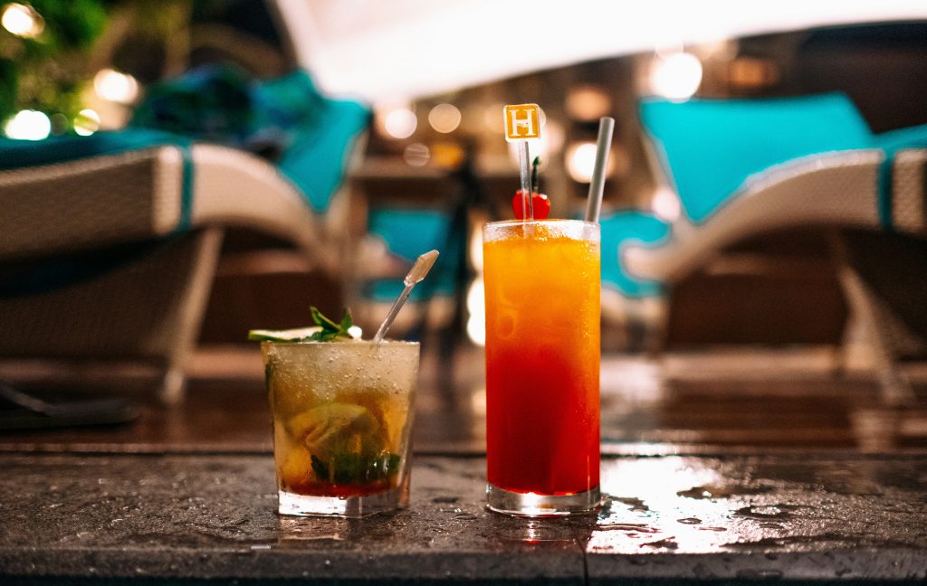 Two cocktails sitting on the edge of the pool.