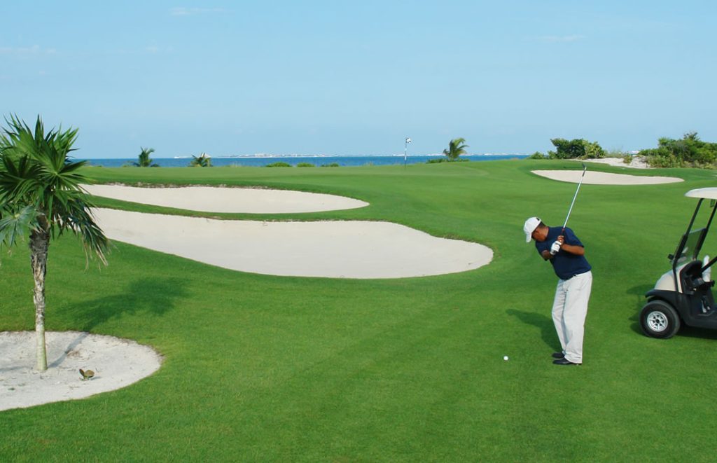 Man swinging a golf club on the green