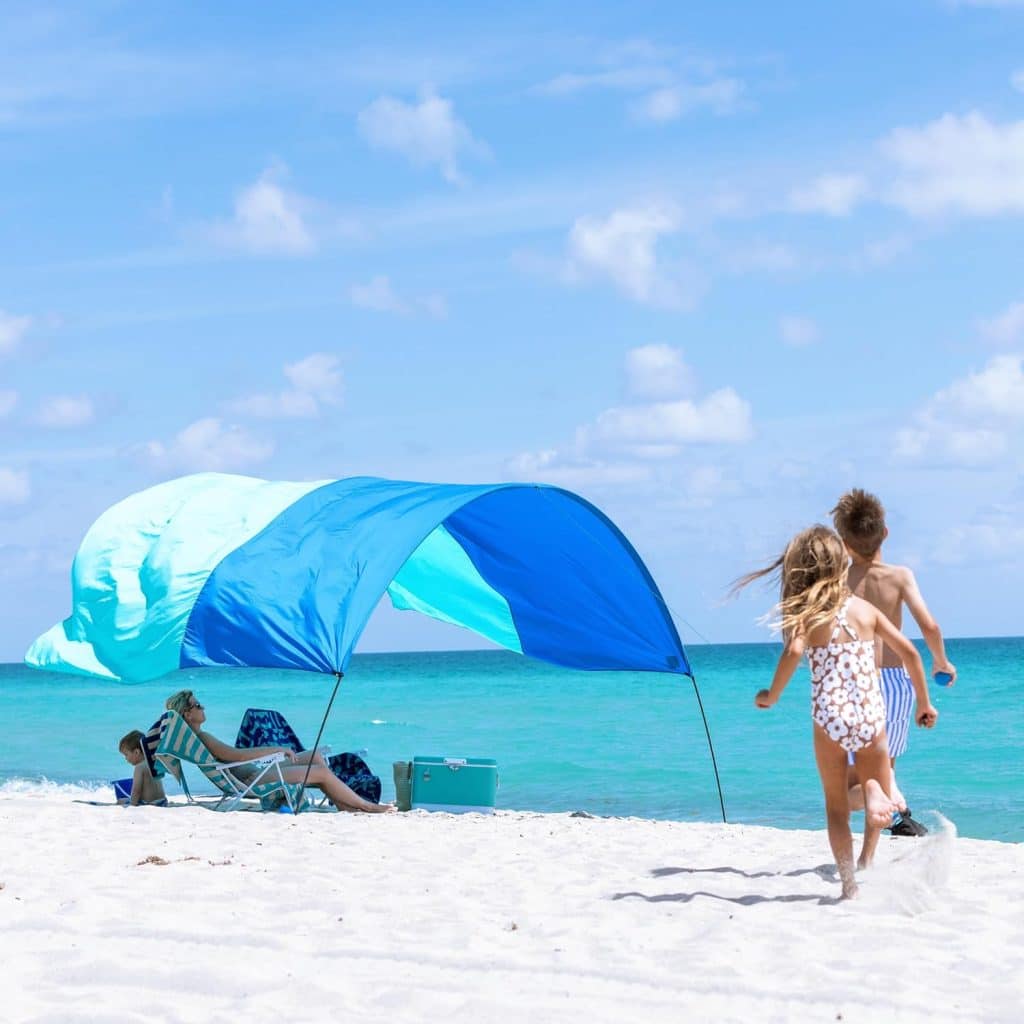 blue kite-like shade covering two beach goers