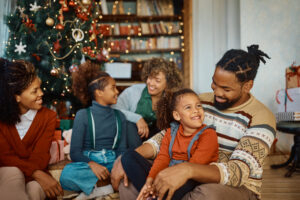 Happy African American extended family enjoying in Christmas day at home. Focus is on father and daughter talking.