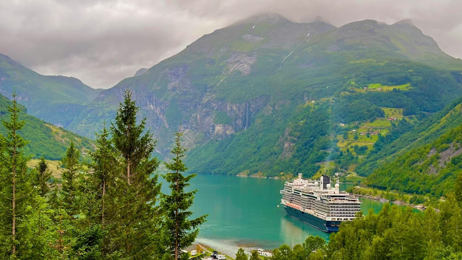 Cruise ship in water surrounded by the Norwegian Fjords mountain range. Best places to visit in May in Europe.