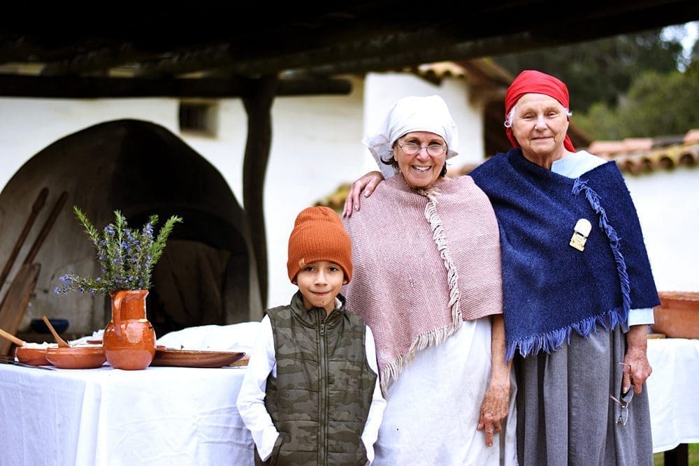 two ladies in shawls and hats with child in beanie