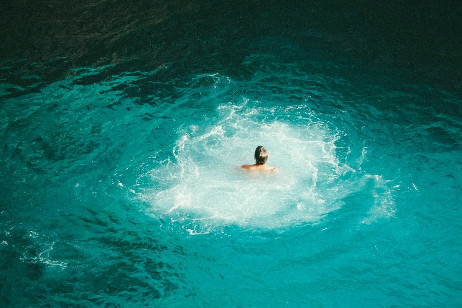 Man swimming in blue Jamaican waters. Best hotels in Jamaica for families.