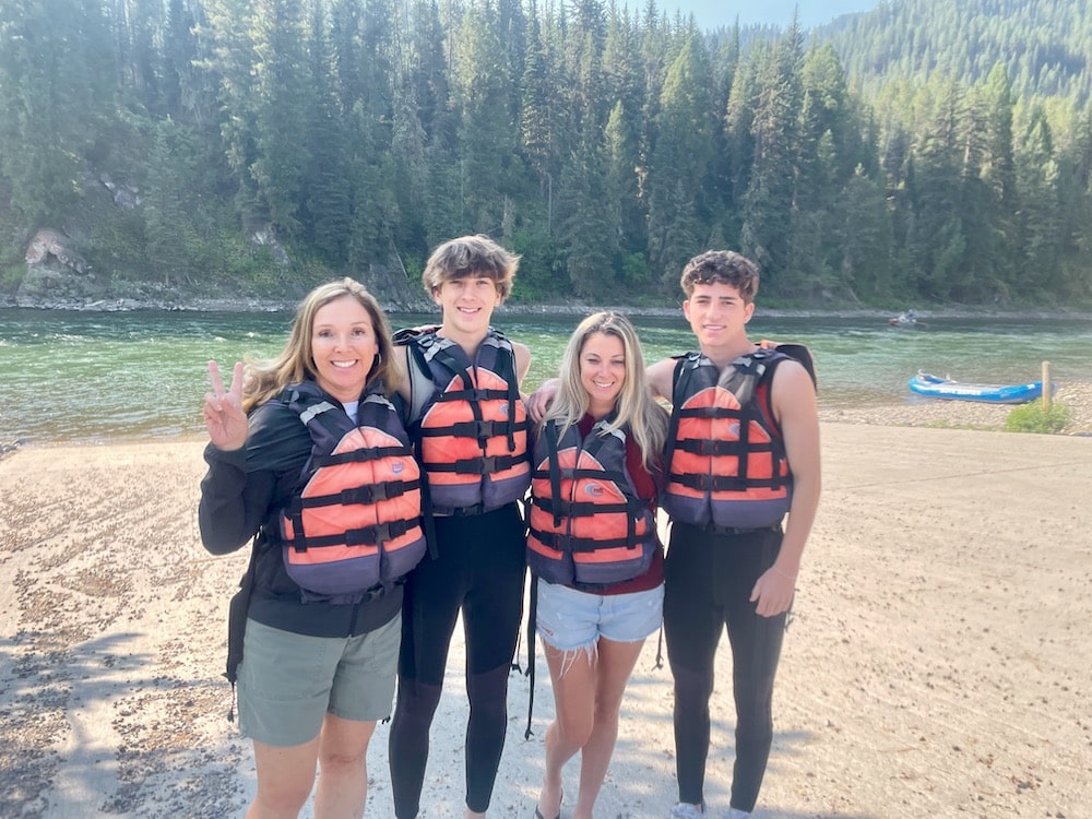 families in life vests by river