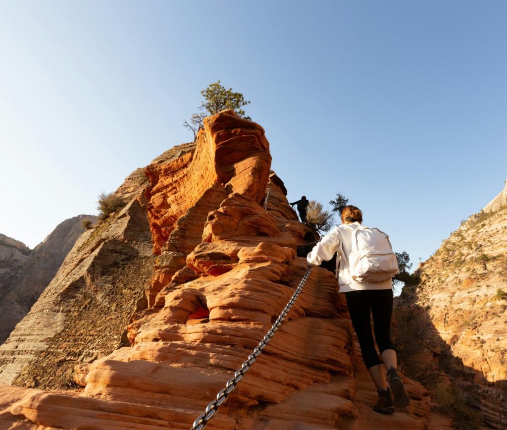 A hiker using set chains to climb Angels Landing in Zion.