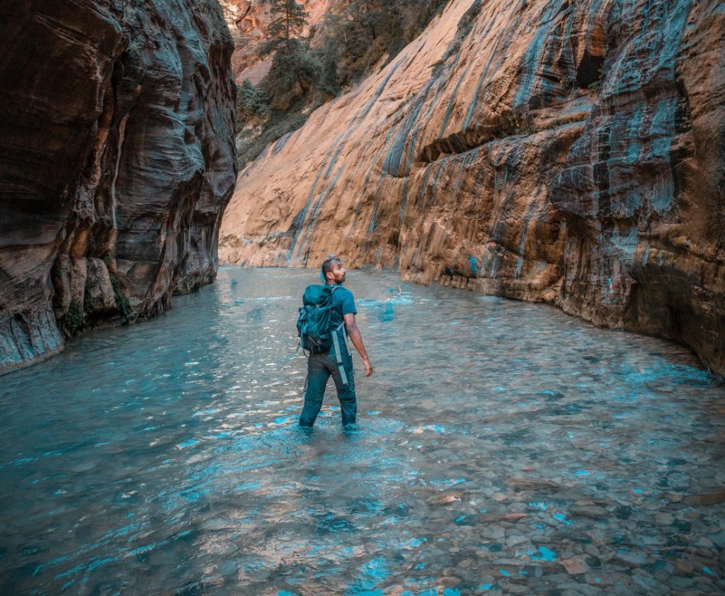 A hiker wading through the river during the narrows hike.