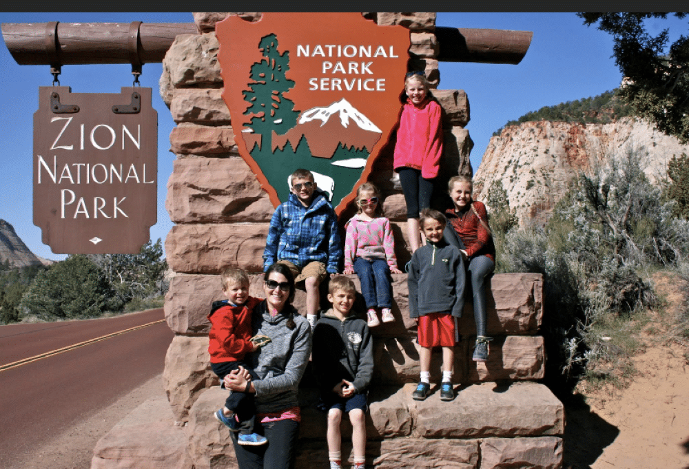 A family at the entrance of Zion National Park.