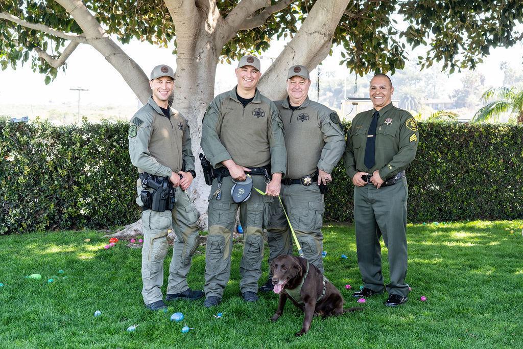 officers with K9 dog and easter eggs on grass