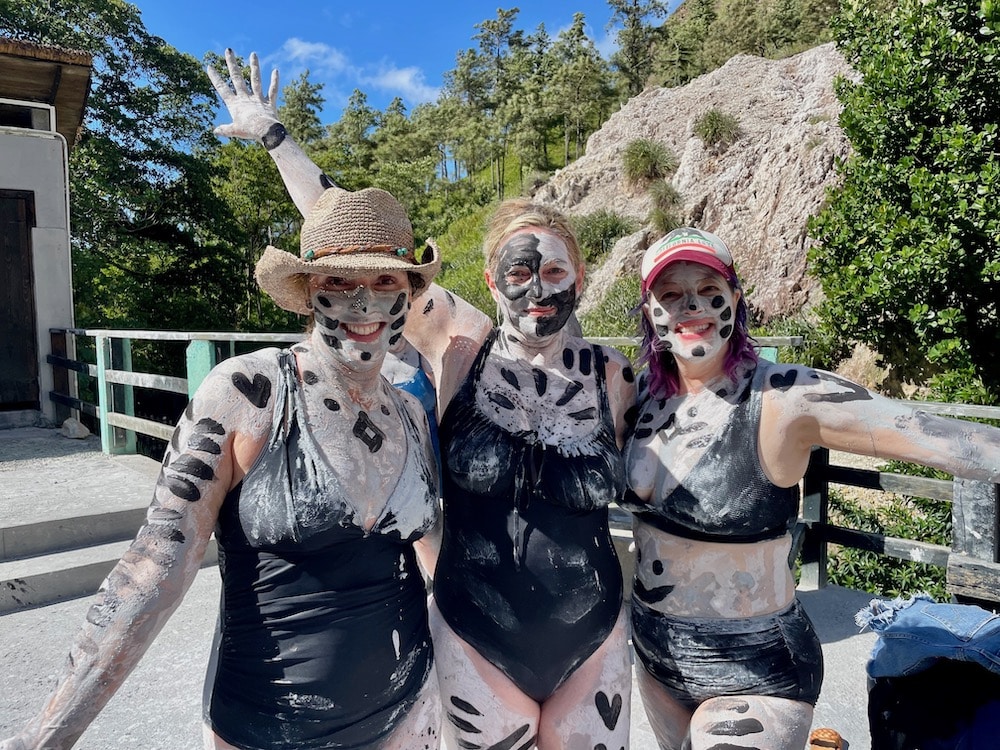 three women in bathing suits and mud on bodies