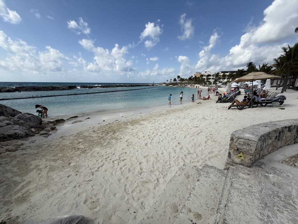protected blue ocean water by rock reef and families in and around it.