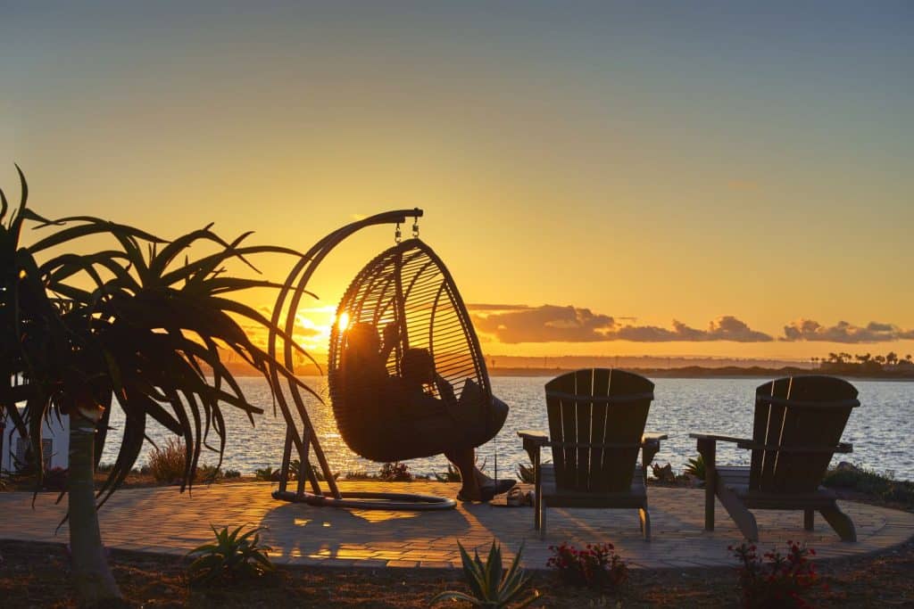 person sitting in egg chair swing during sunset
