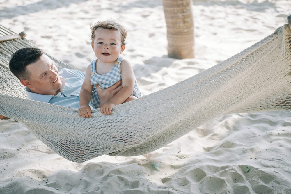 dad and toddler in hammock over sand