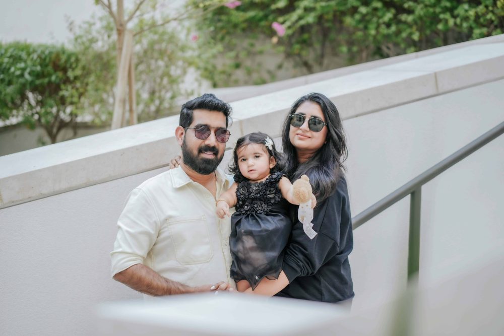 mom on right, dad on left, toddler girl with brown hair in middle.