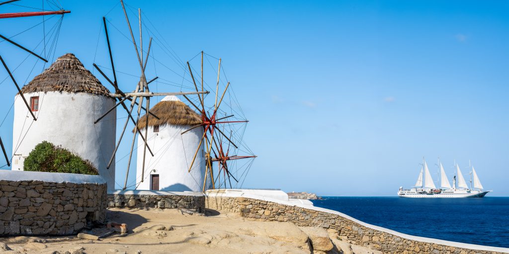 two windmills by the ocean and white boat