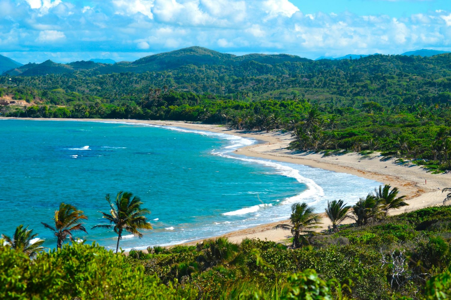 Puerto Plata in the Dominican Republic. Lush greenery surrounding turquoise waters and golden sand. Cheap beach trips.