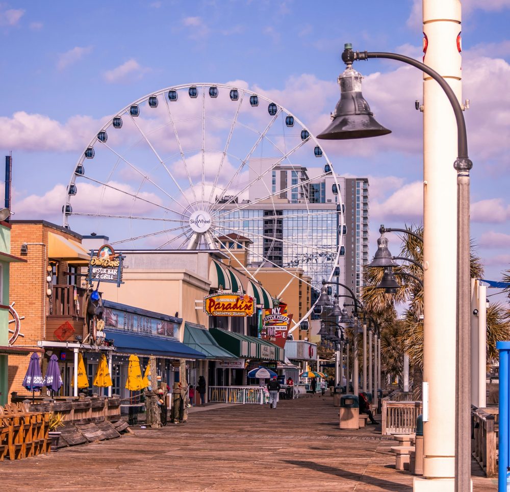 Beach Boardwalk with shops and Ferris wheel in the distance for a Labor Day weekend getaway.